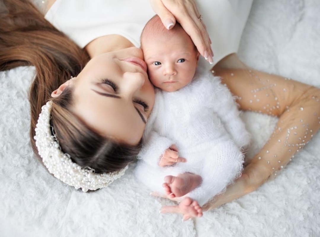 Ema ja peog lamamas selili, vastsündinu poja pea toetab ta ema õlale. Ema vaatab õnnelikult oma peoga, poeg vaatab kaamerasse. Mõlemal on seljas valged riided.